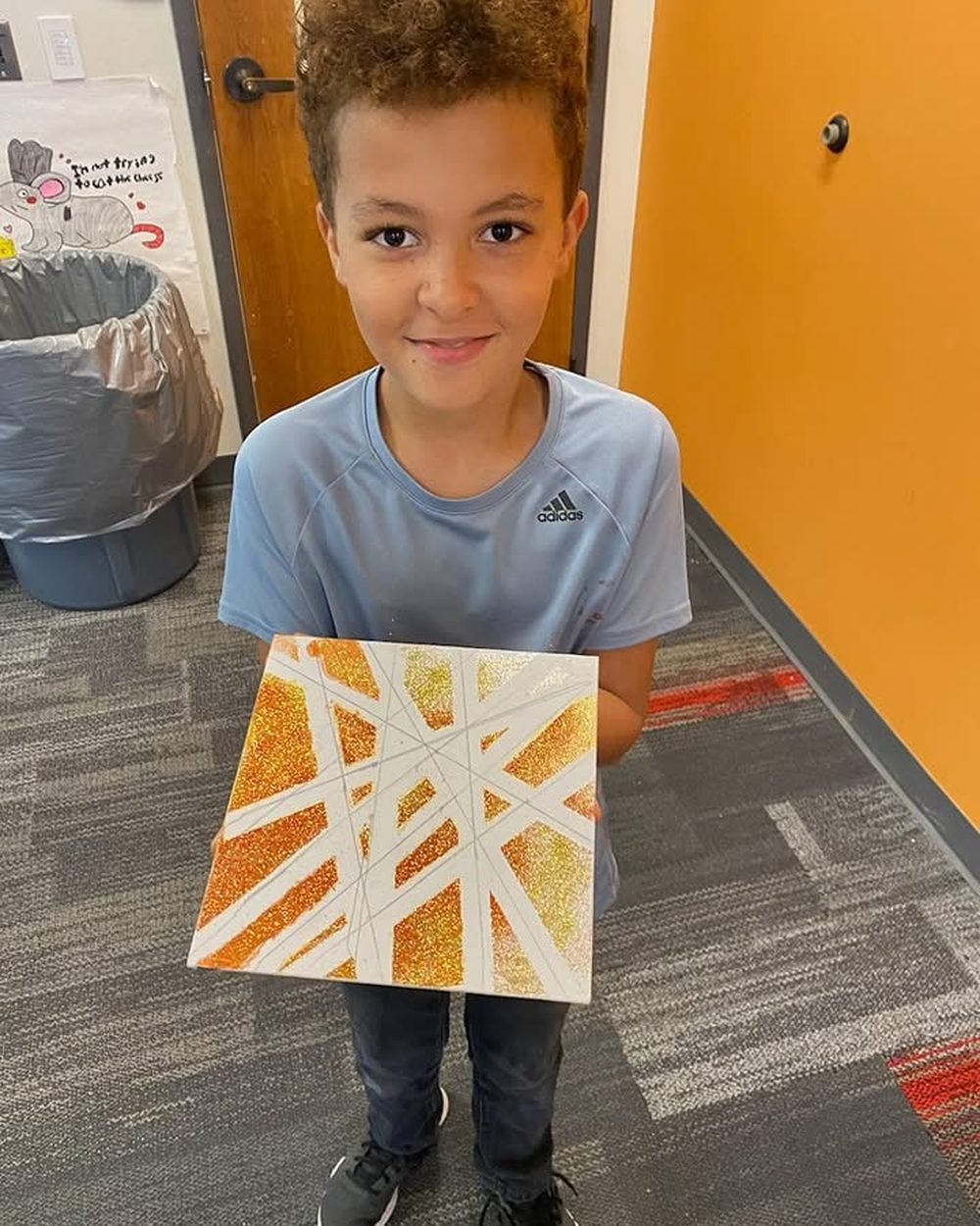 A TriPoint student proudly holding a geometric mixed-media art piece.