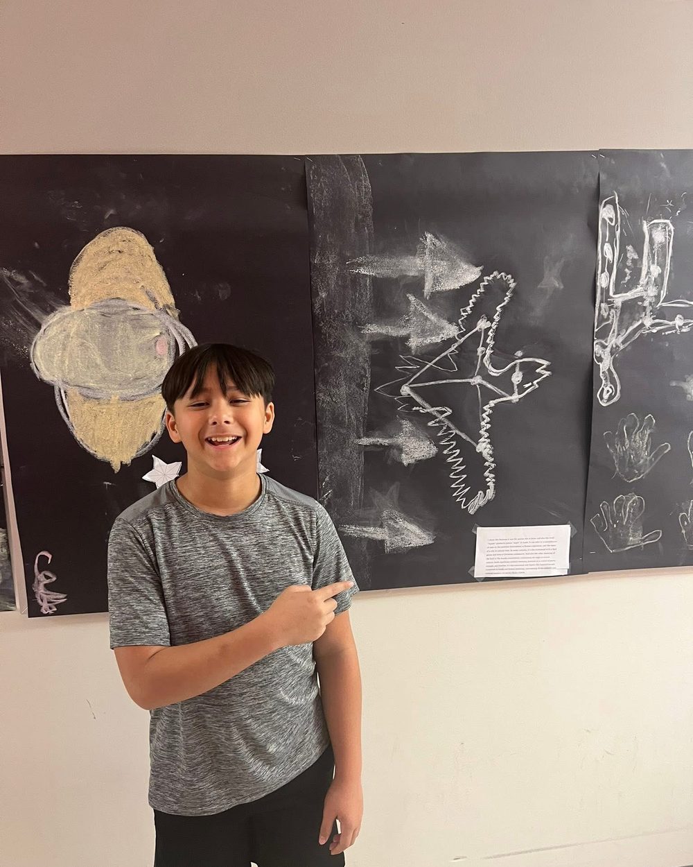 A TriPoint student smiling proudly next to chalk artwork on display.