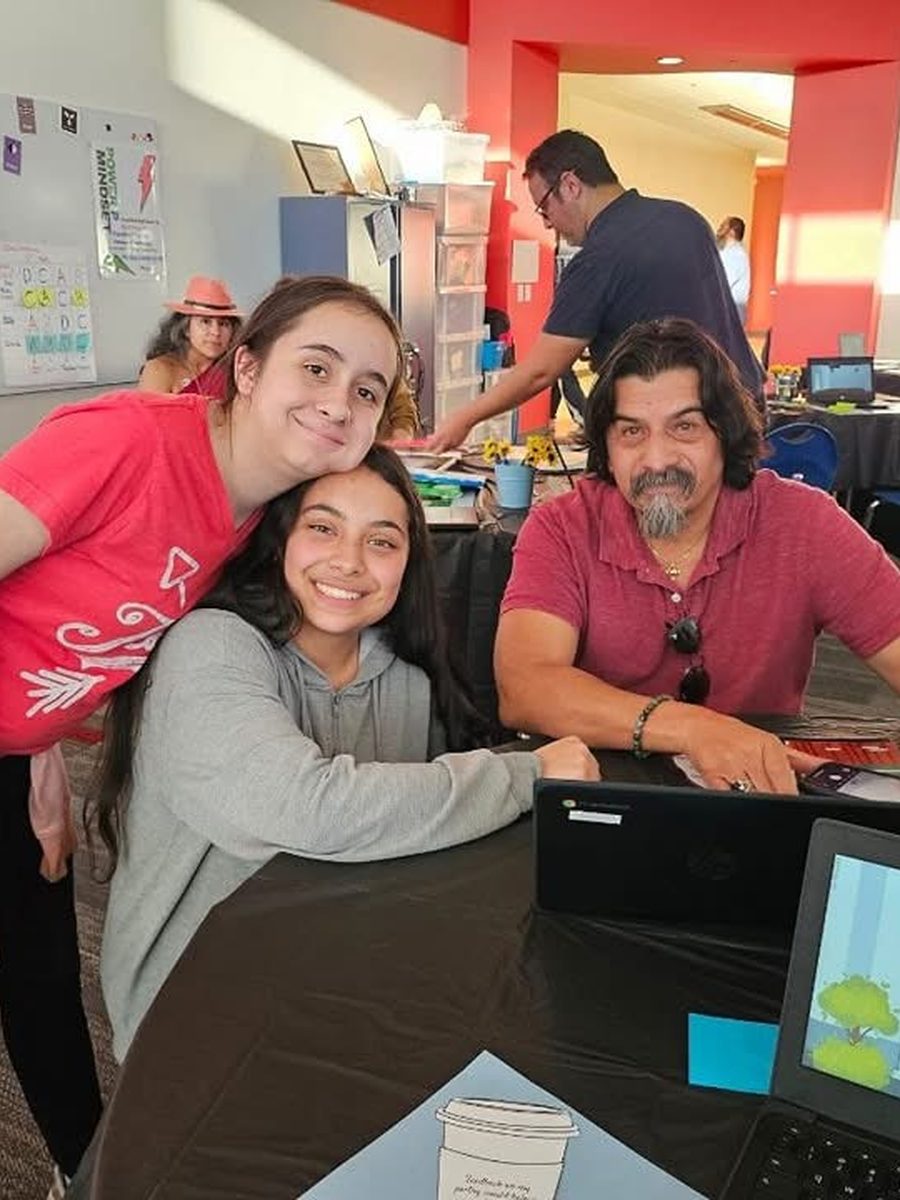 Two TriPoint students leaning in close with a teacher around a laptop.